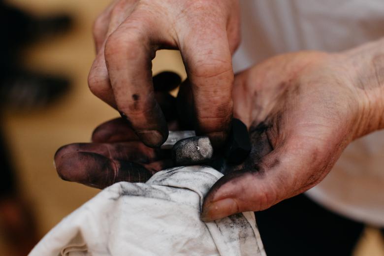 Hands holding charcoal and a cloth