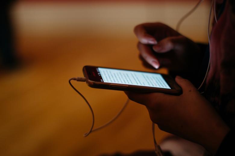 Someone holding a phone in their hands with headphones attached