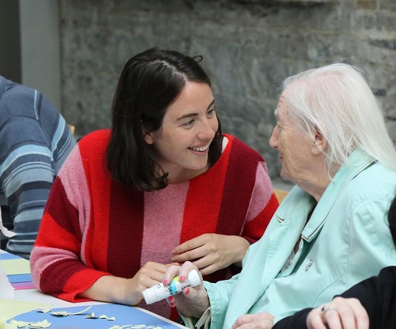 Photo of a young woman and older woman making crafts in an art workshop.