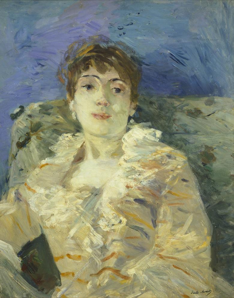 A woman reclines on a patterned divan. She wears a cream dress with orange markings and a ruffled neckline, and drop earrings. The wall behind her is blue.