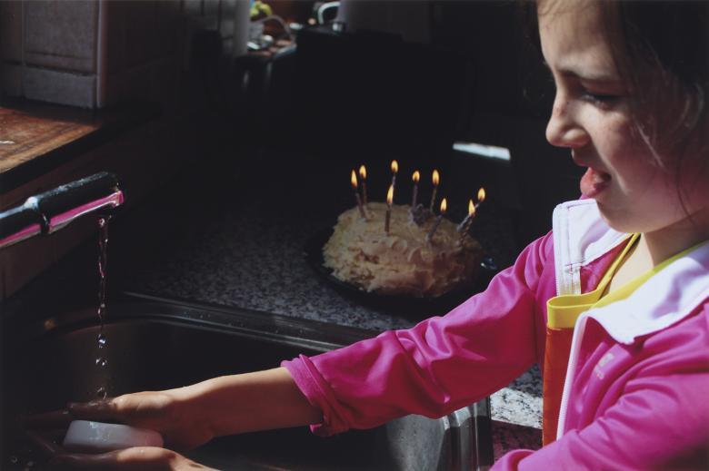 Photograph portrait of young girl washing her hands at the kitchen sink