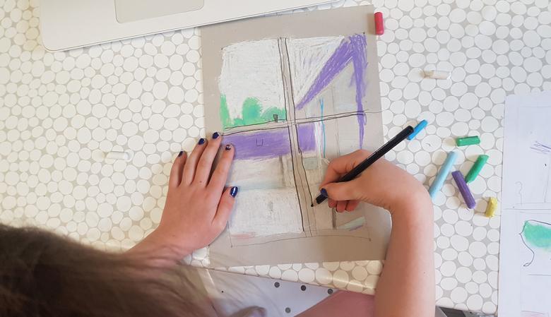 A photograph of a child drawing, taken from above