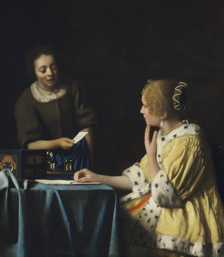 A woman in a yellow coat trimmed with ermine sits at a table writing a letter. She is looking at her maid, dressed in brown, who is speaking to her and handing her a note.