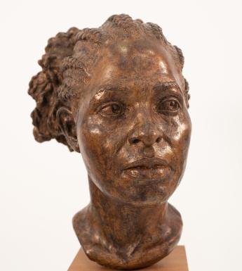 A resin bust on a mahogany base.