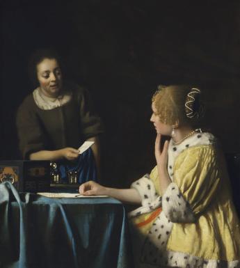 A woman in a yellow coat trimmed with ermine sits at a table writing a letter. She is looking at her maid, dressed in brown, who is speaking to her and handing her a note.