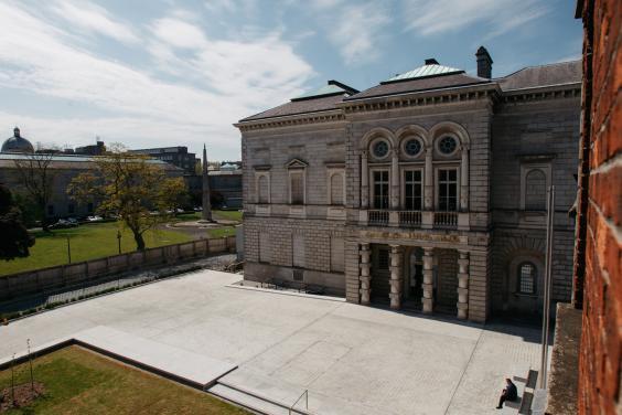 A colour photograph showing the stone facade of the Gallery's historic wing taken from a height. The sky is blue and streaked with white clouds.