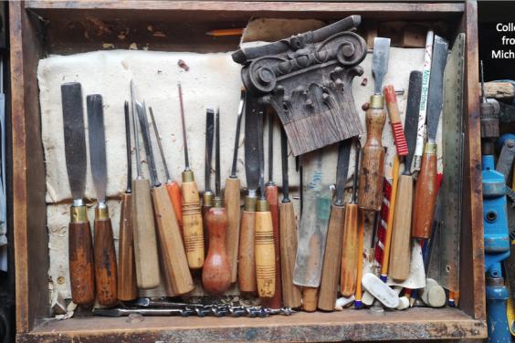 Photo of a variety of chisels in a wooden drawer.