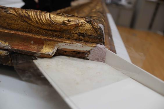 Damaged corner of a gilded picture frame being repaired