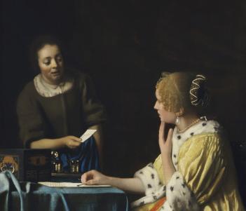 A woman in a yellow coat trimmed with ermine sits at a table writing a letter. She is looking at her maid, dressed in brown, who is speaking to her and handing her a note.